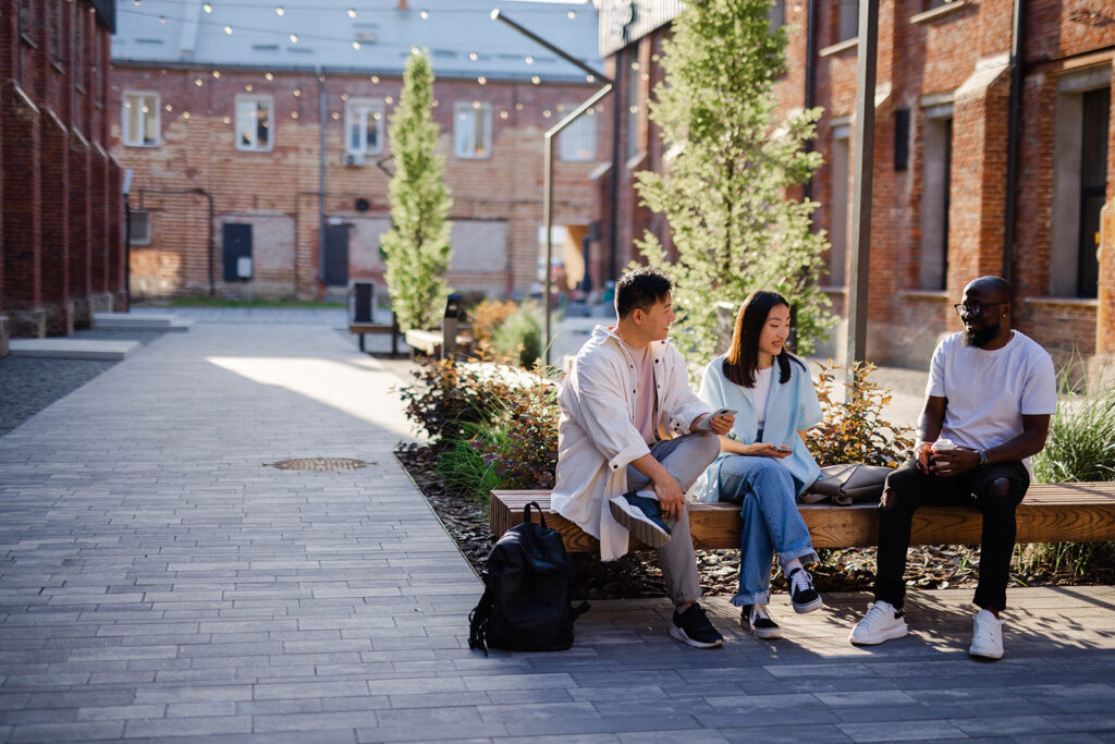 Drei Studenten im Outdoor-Bereich zwischen restaurierter Backsteinarchitektur