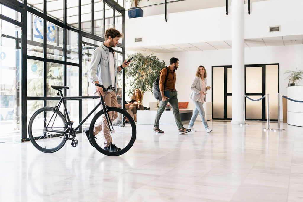 Junge Office Worker erscheinen am Arbeitsplatz, mit Smartphone, Tablet und Fahrrad